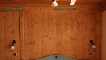 Una habitación con paneles de madera, una cama, dos mesitas de noche y un ventilador de techo.
