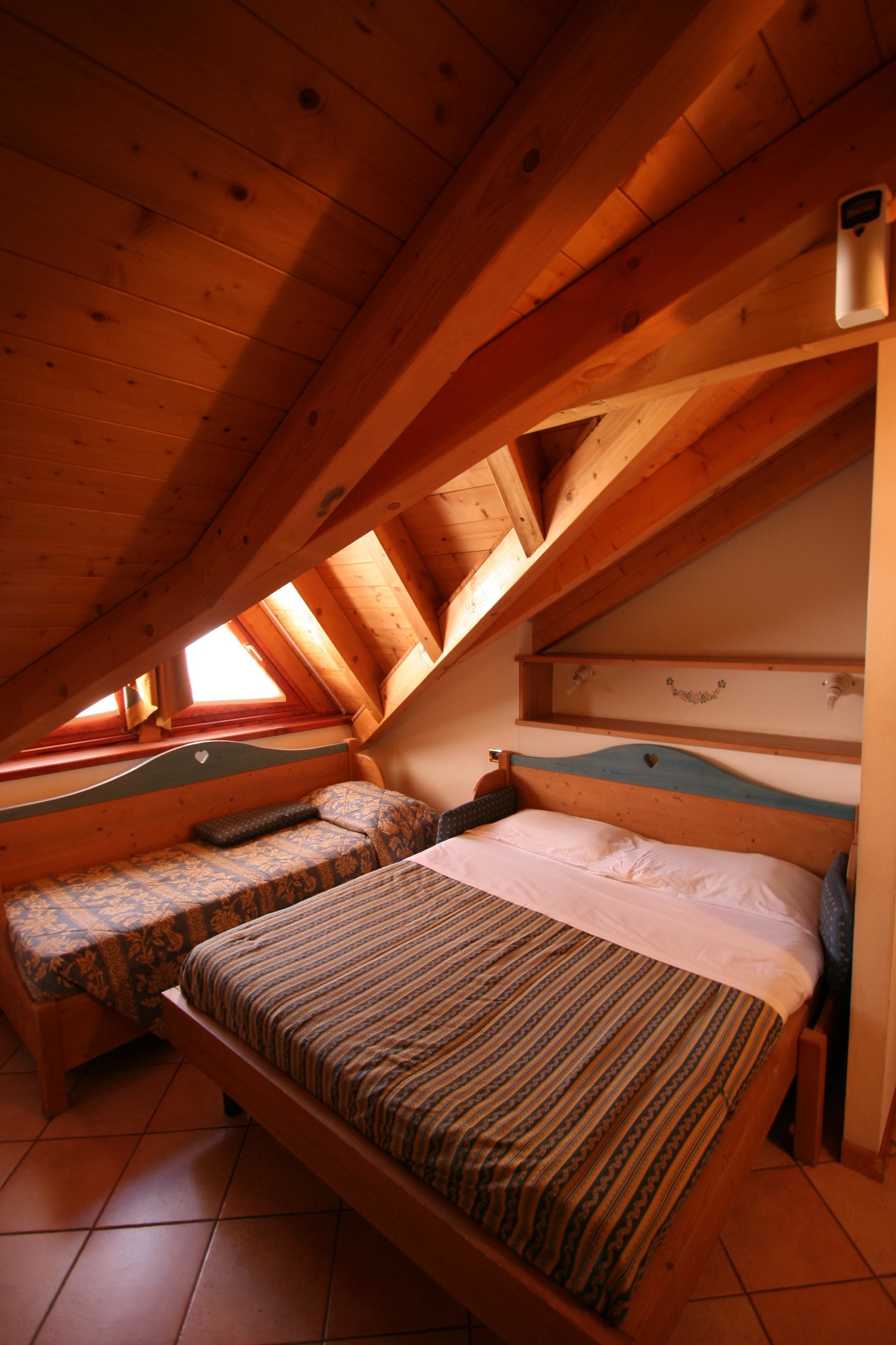Una camera da letto mansardata accogliente, con due letti, travi in legno e soffitto inclinato.