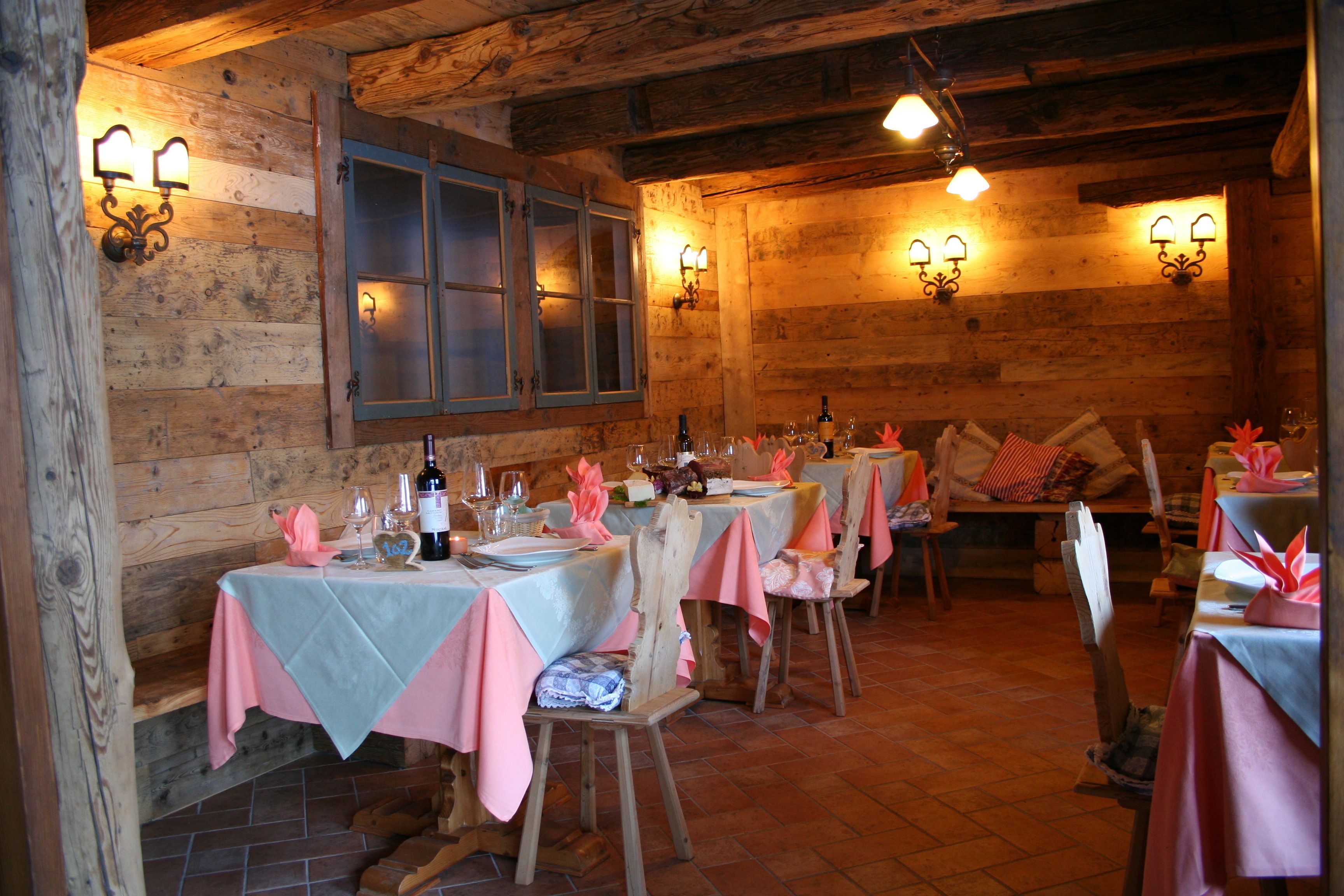 Un interior rústico de madera con mesas dispuestas para comer, sillas sencillas y un ambiente cálido.