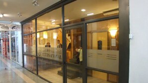 A hotel entrance with a reception desk, glass doors, and a tiled floor.