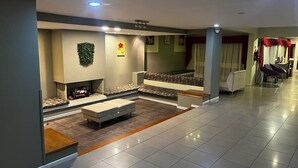 A modern hotel lobby with a seating area, a fireplace, and a reception desk.
