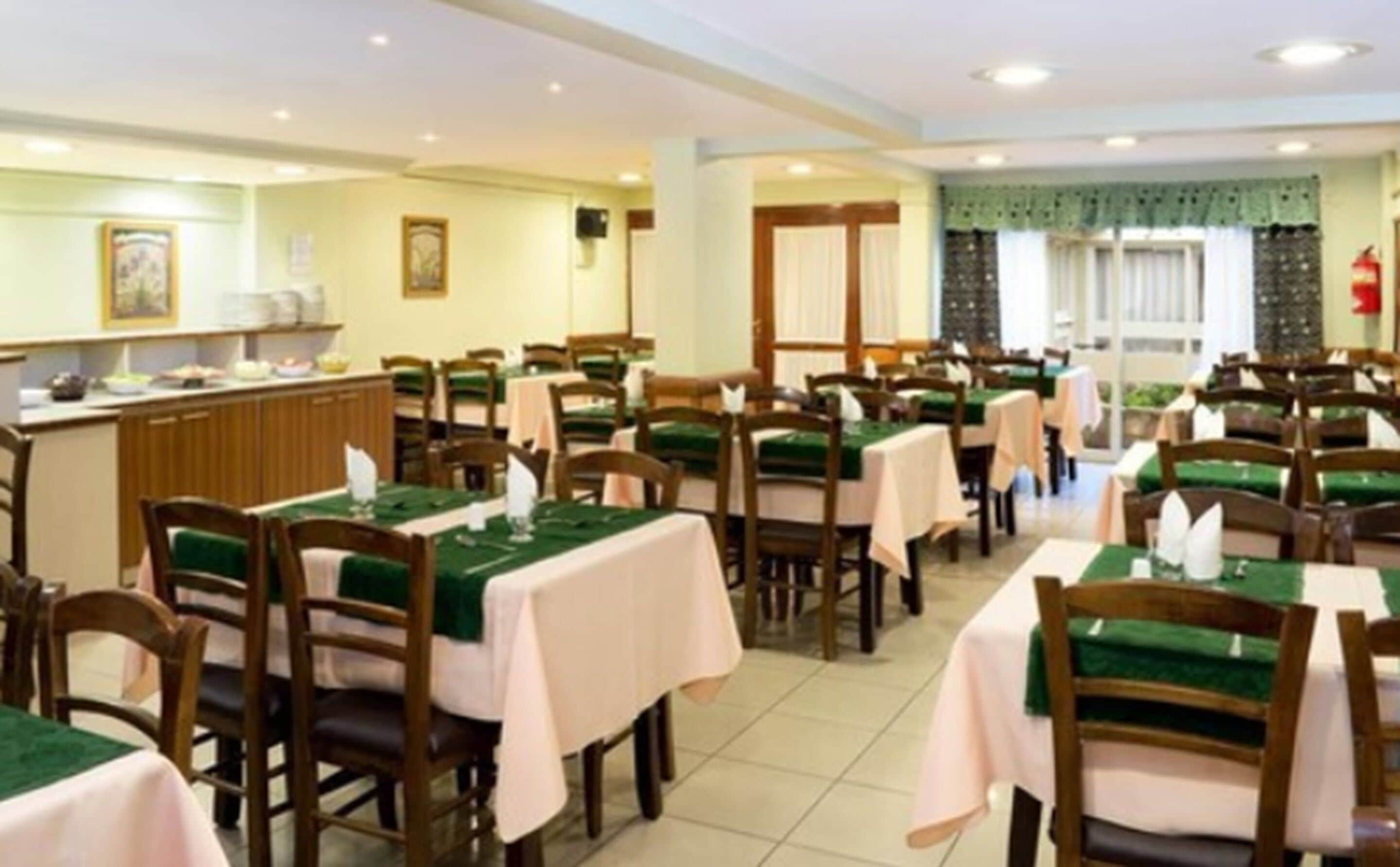 A dining area with multiple tables and chairs, a counter with a menu, and a window with curtains.