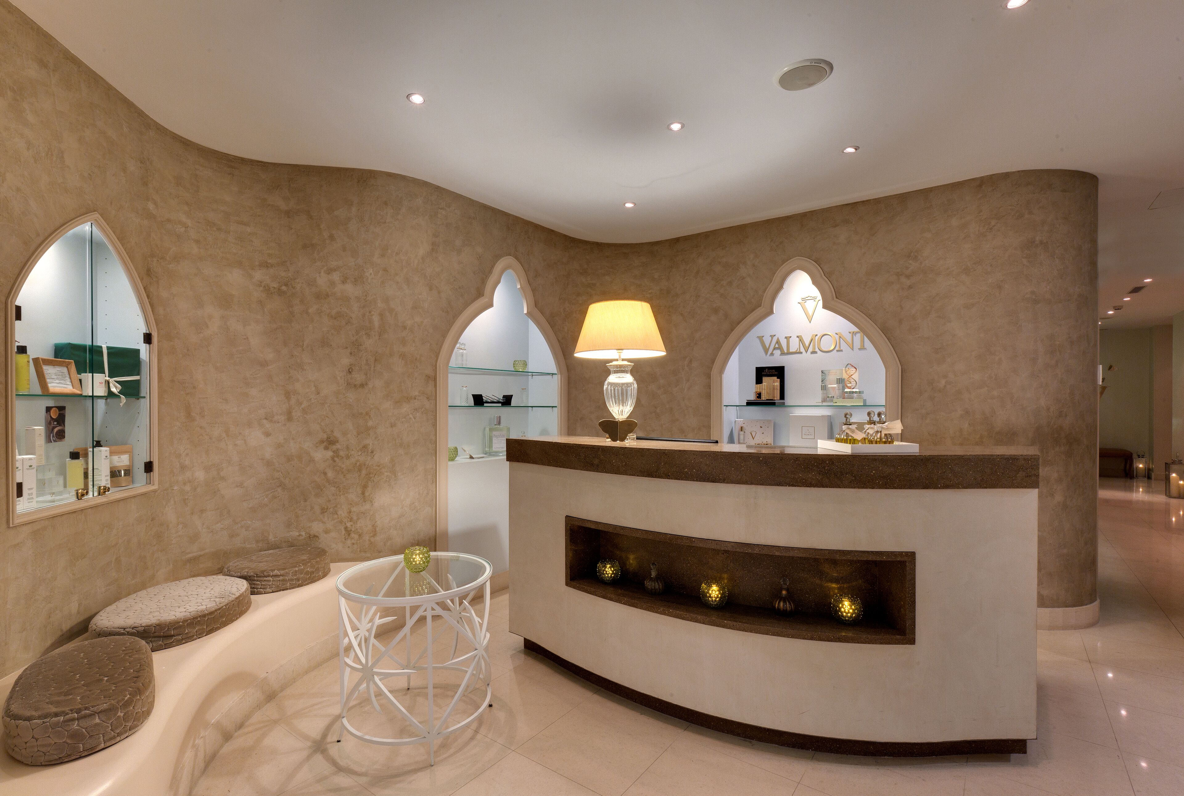 A reception area with a curved counter, a lamp, and a sign that reads 'VALMONTE.'