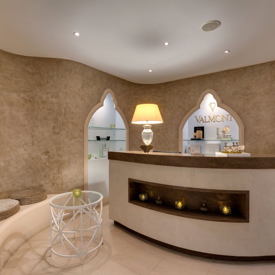 A reception area with a curved counter, a lamp, and a sign that reads 'VALMONTE.'