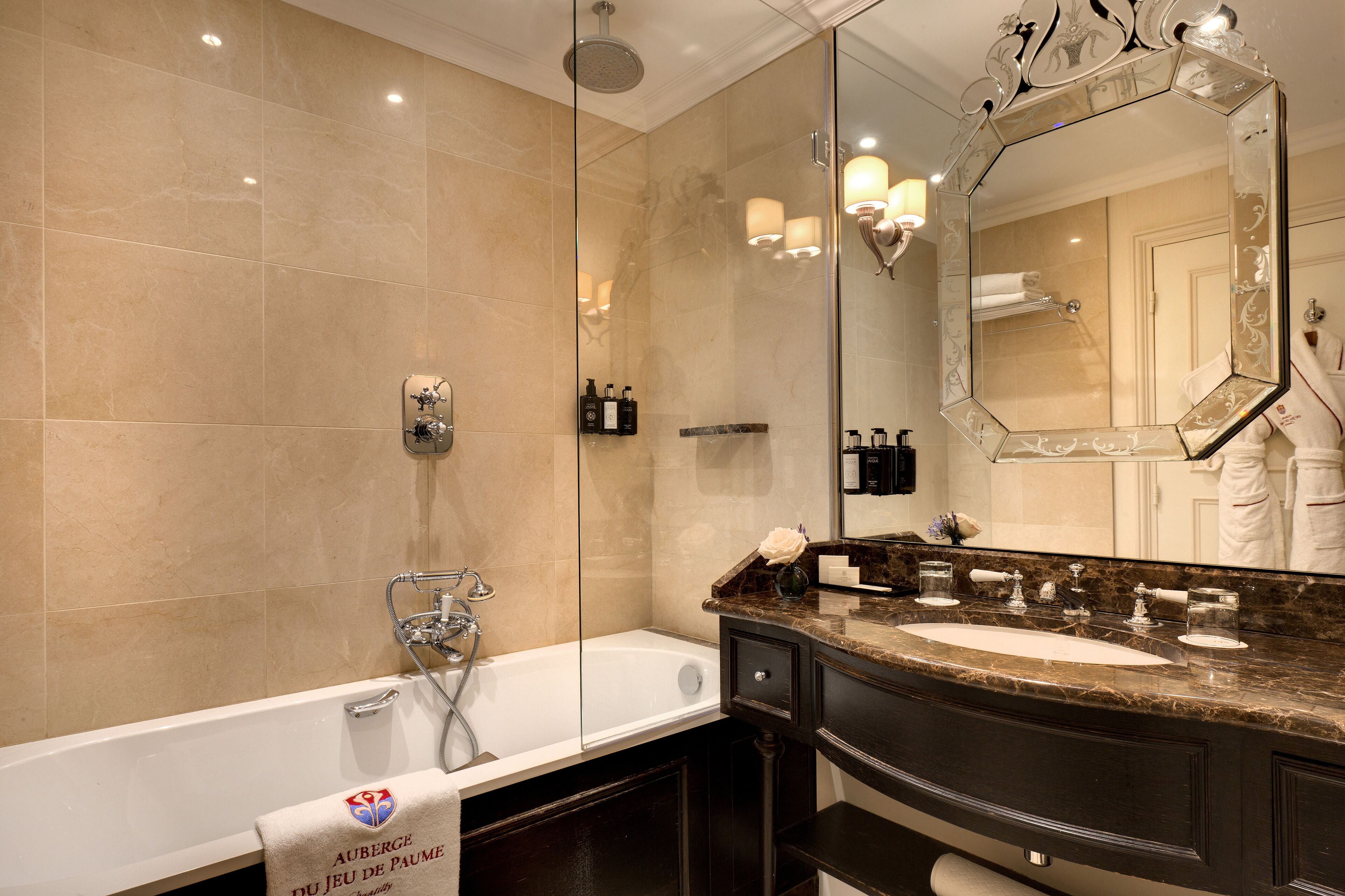 Un baño con un espejo grande, una bañera y un tocador con lavabo.