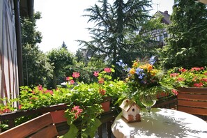 Un banc en bois et une table sur laquelle se trouvent une nichoir et un vase de fleurs.