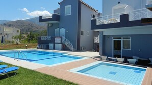 A two-story building with a swimming pool, outdoor seating, and a view of mountains. - Hotel Athena (Apokoronas)