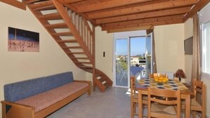 A room with a wooden staircase, a bench, a table with chairs, and a view through a glass door. - Hotel Athena (Apokoronas)
