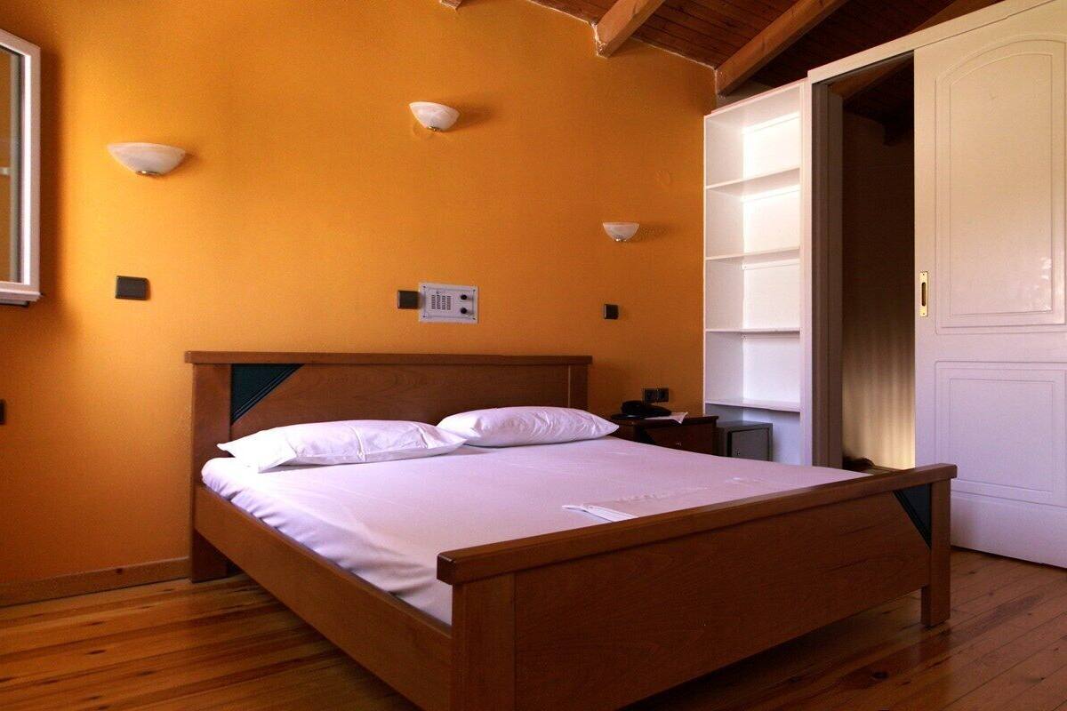 A bedroom with a wooden bed, white wardrobe, and built-in shelves.