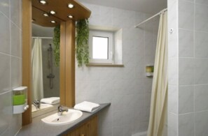 Un baño moderno con lavamanos, espejo y ducha.