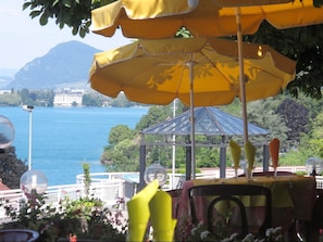 Um terraço com guarda-sóis amarelos, vista para um lago e um coreto.