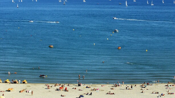 Una playa con numerosos barcos y gente.