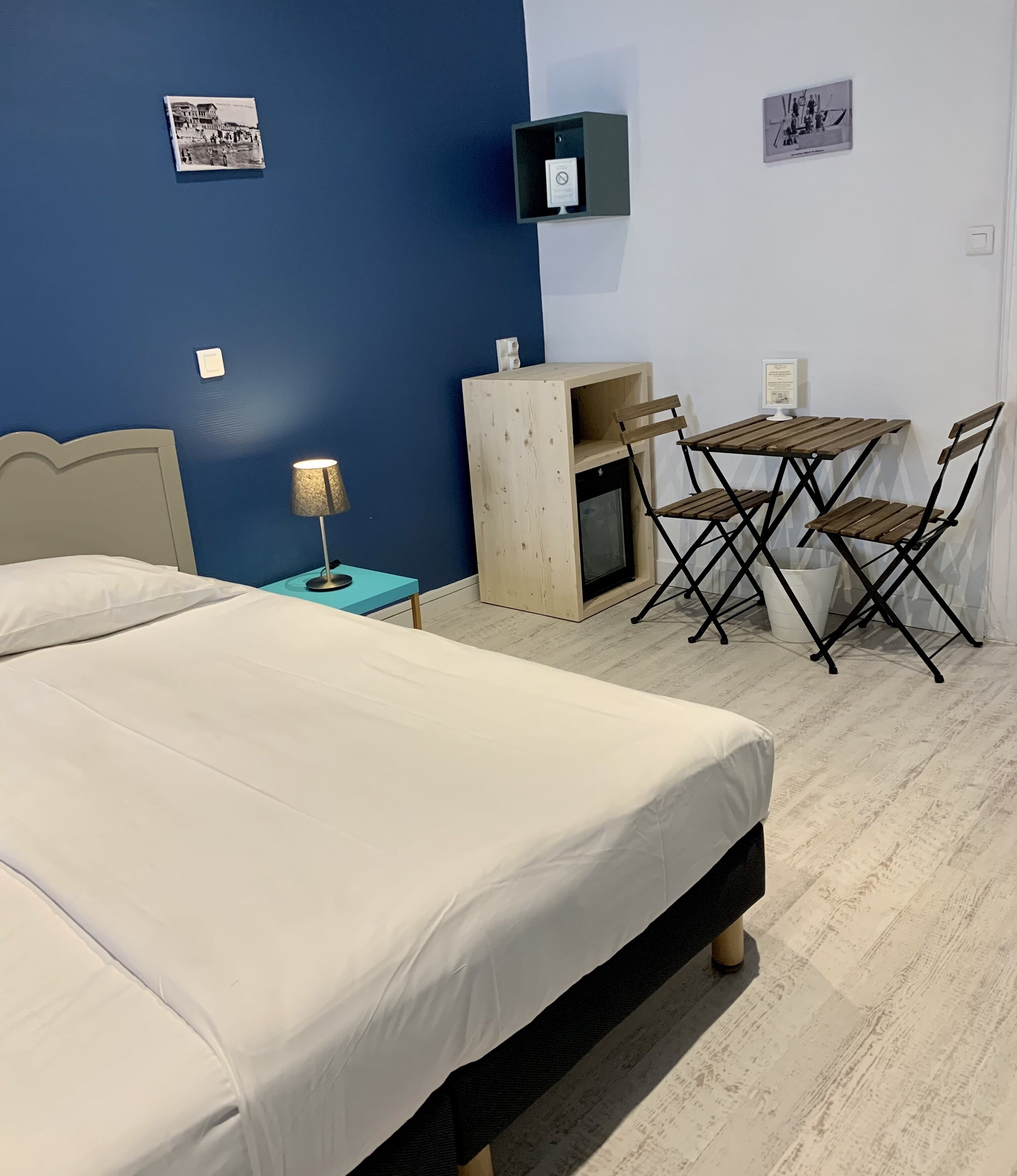 A hotel room with a bed, a desk, a chair, a small table, and a wooden cabinet.