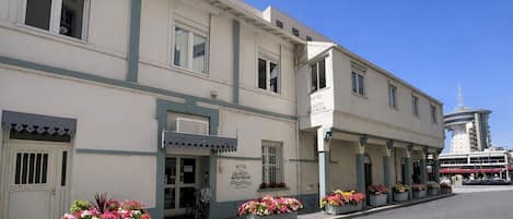 A hotel with a classic facade, multiple windows, and a sign indicating it is the 'Hotel Le Petit Boigneur.'