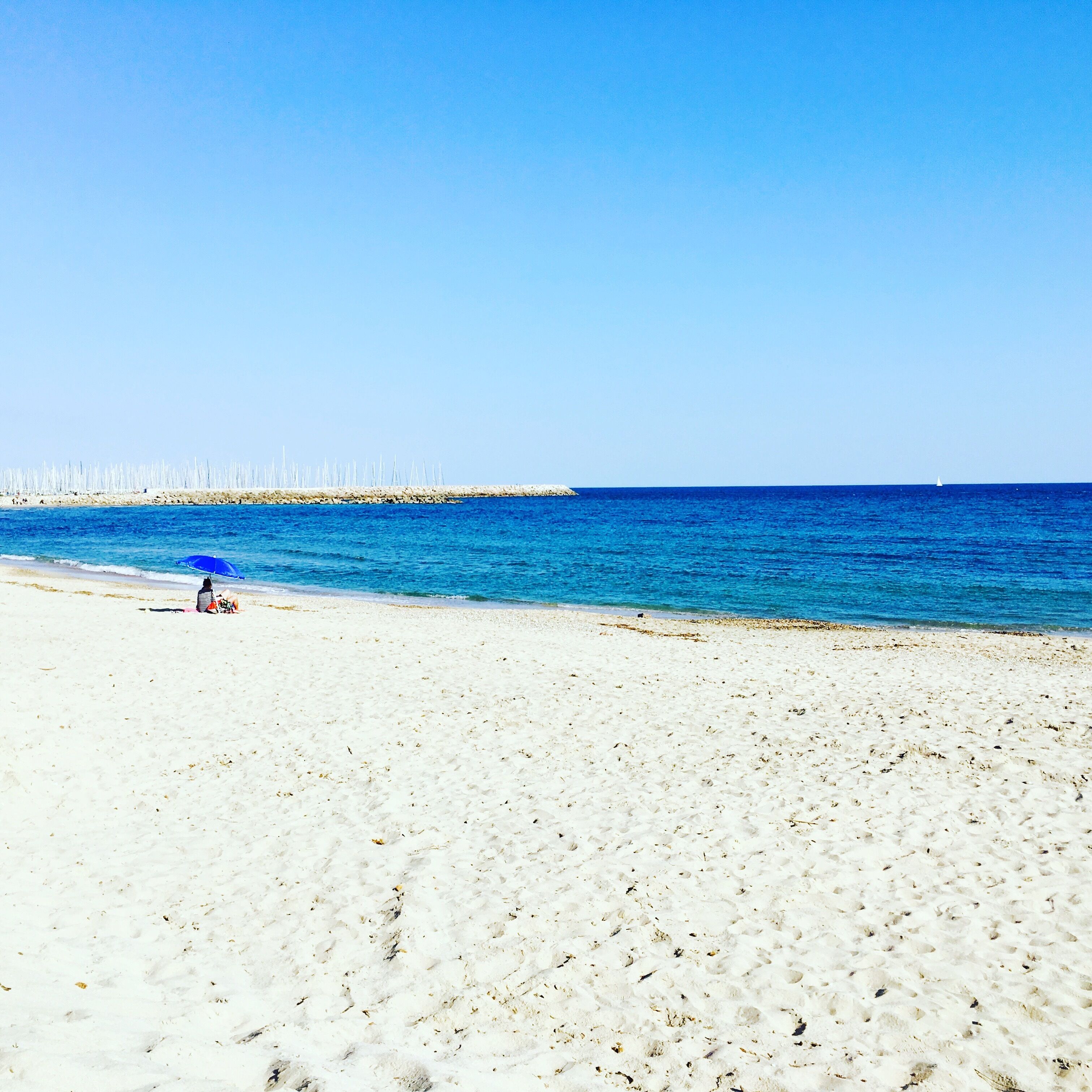 Une plage de sable blanc, un ciel bleu azur et une mer calme.