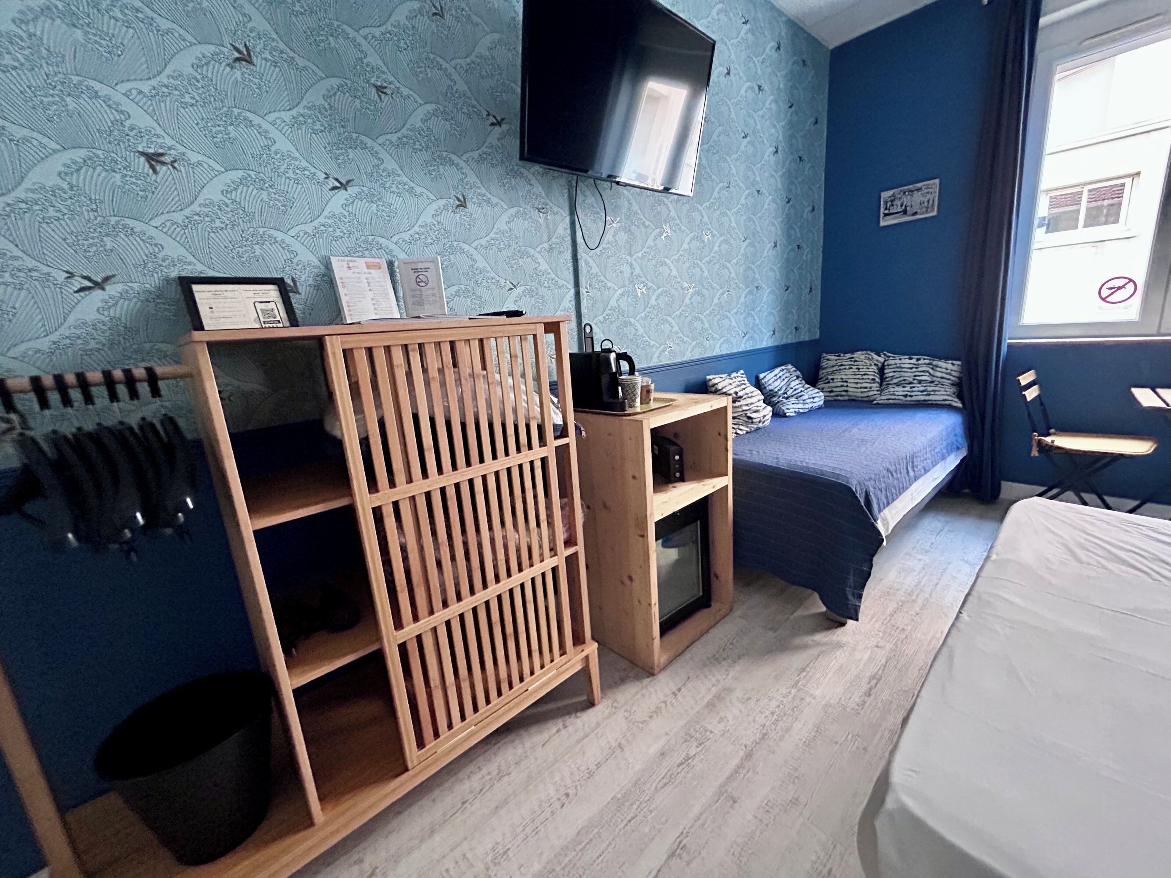 Ein Schlafzimmer mit einem Bett, einem an der Wand montierten Fernseher, einem Holzregal und einem Fenster mit Blick.