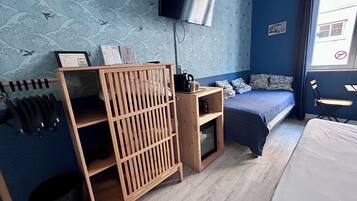 Ein Schlafzimmer mit einem Bett, einem an der Wand montierten Fernseher, einem Holzregal und einem Fenster mit Blick.