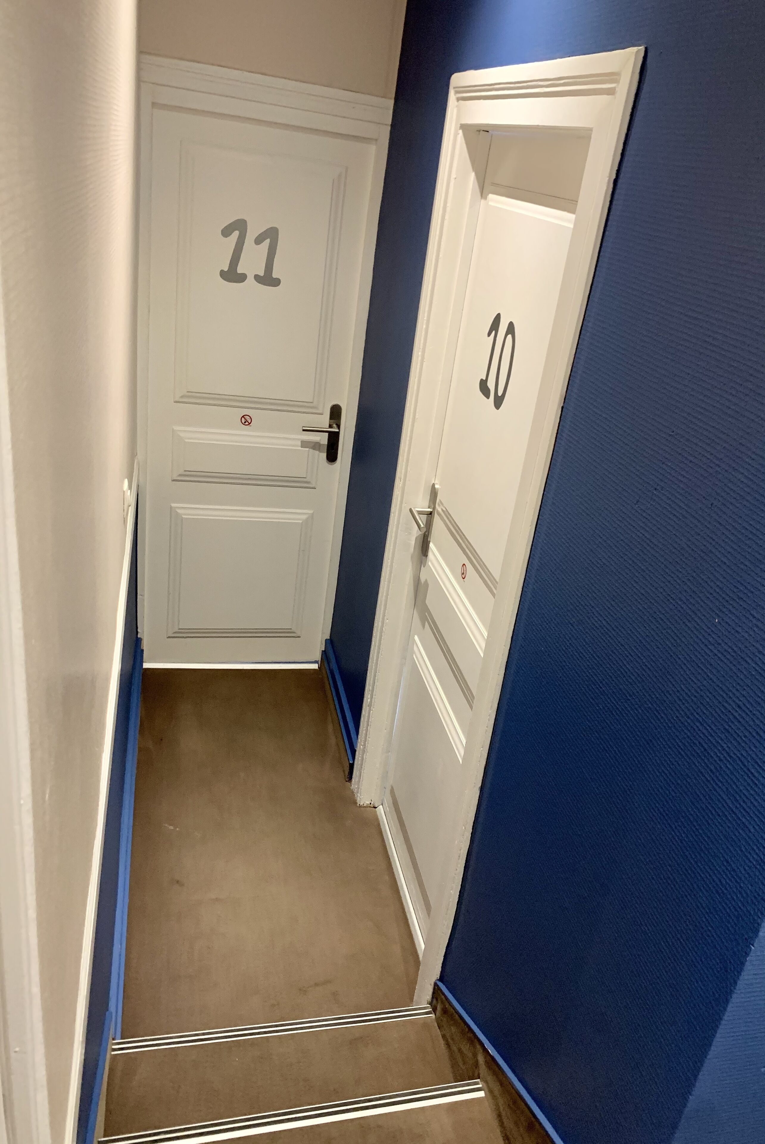 Ein schmaler Flur mit zwei Türen, auf denen 11 und 30 stehen, der zu Zimmern führt.
