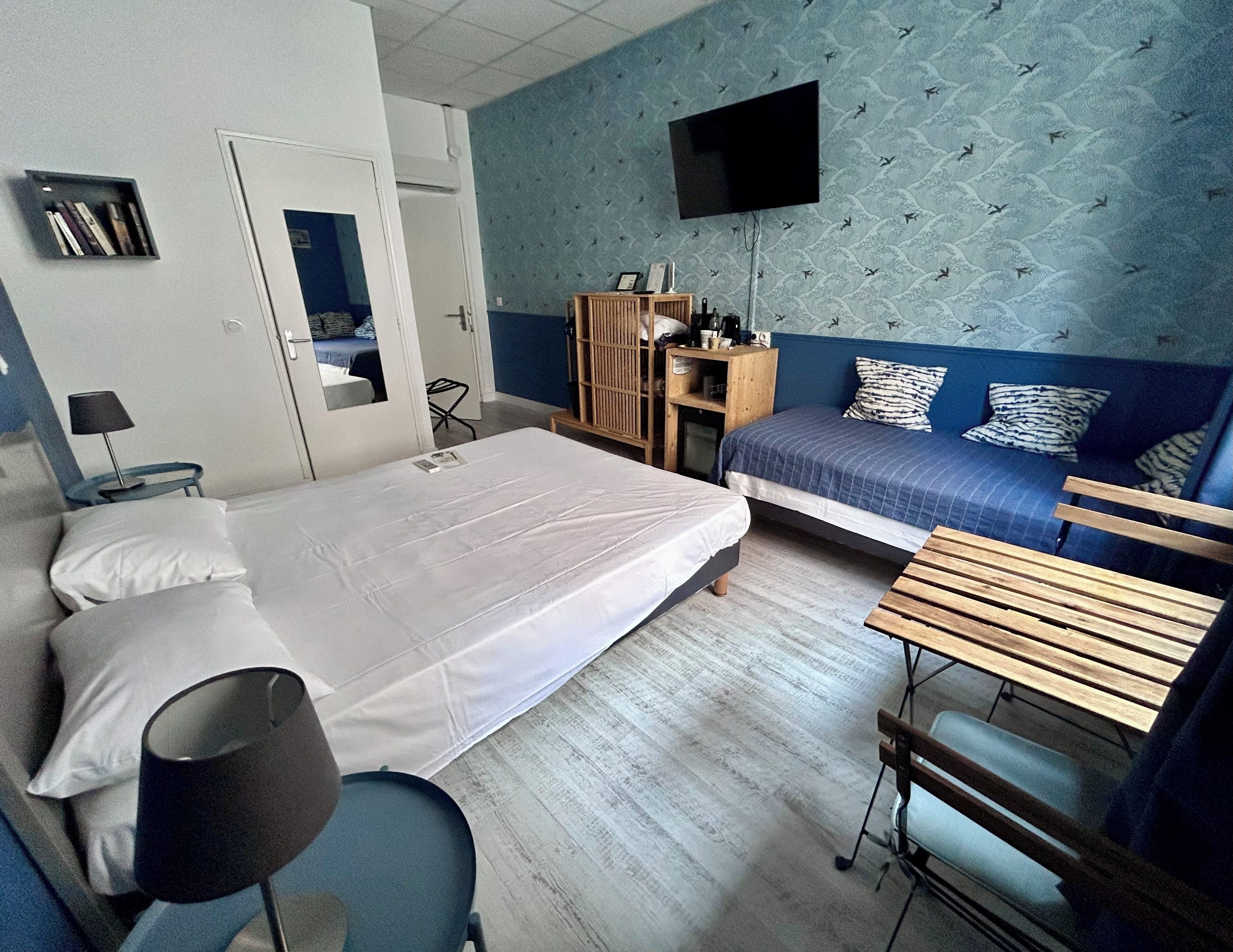 A hotel room with a bed, a desk, a chair, a TV, and a wardrobe.