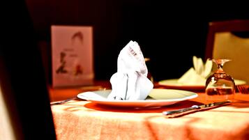 Une table dressée avec une serviette pliée, un verre et des couverts.