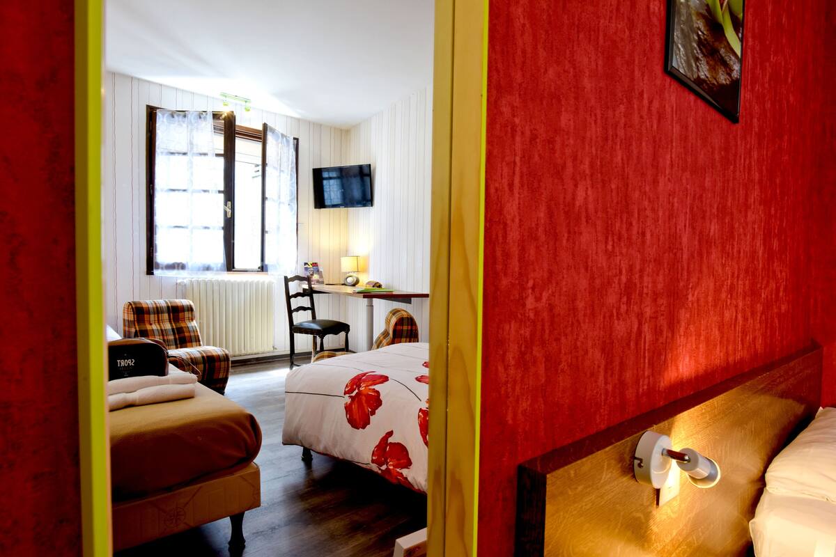 A hotel room with a bed, a chair, a desk, and a television.