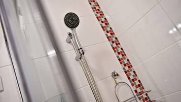 Une douche équipée d’un pommeau de douche à main et d’un robinet fixé au mur.