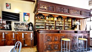 Un'area bar con armadietti in legno, una macchina da caffè e sgabelli da bar.