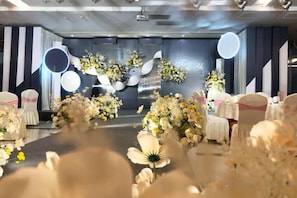 A stage with floral arrangements and a backdrop with a circular design.