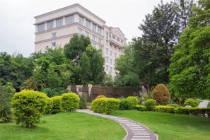 Un bâtiment doté d’un chemin bordé de jardins, entouré de haies et d’arbres bien entretenus.