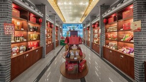 A corridor with shelves of products, a central display table, and a ceiling light fixture. - Min Xi Hotel (Longyan)