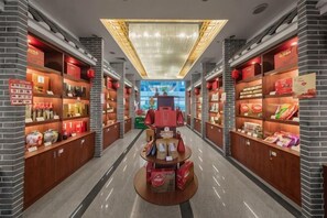 A corridor with shelves of products, a central display table, and a ceiling light fixture. - Min Xi Hotel (Longyan)