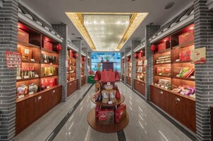 Un pasillo con estanterías llenas de productos, una mesa de exhibición central e iluminación en el techo.