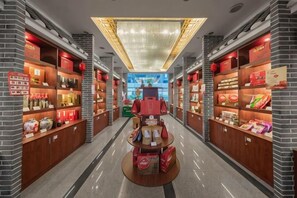Un couloir bordé d’étagères remplies de divers produits, une table centrale servant de présentoir et un luminaire au plafond.