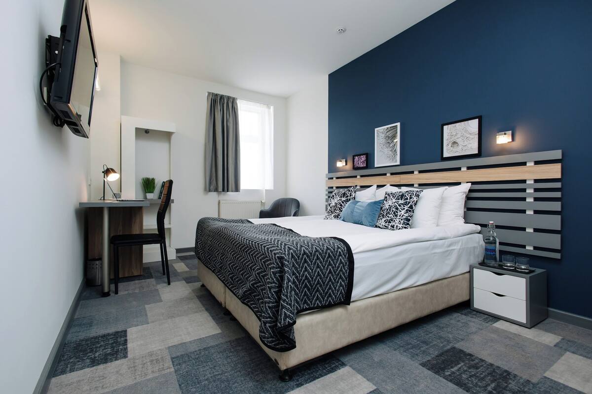 Un dormitorio moderno con cama, mesita de noche y un escritorio con silla.