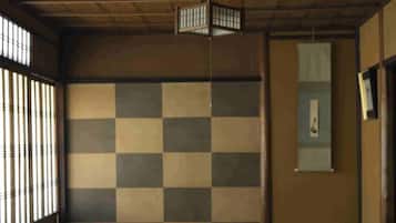 A traditional tatami mat room with a checkered wall, a framed picture, and a sliding door.