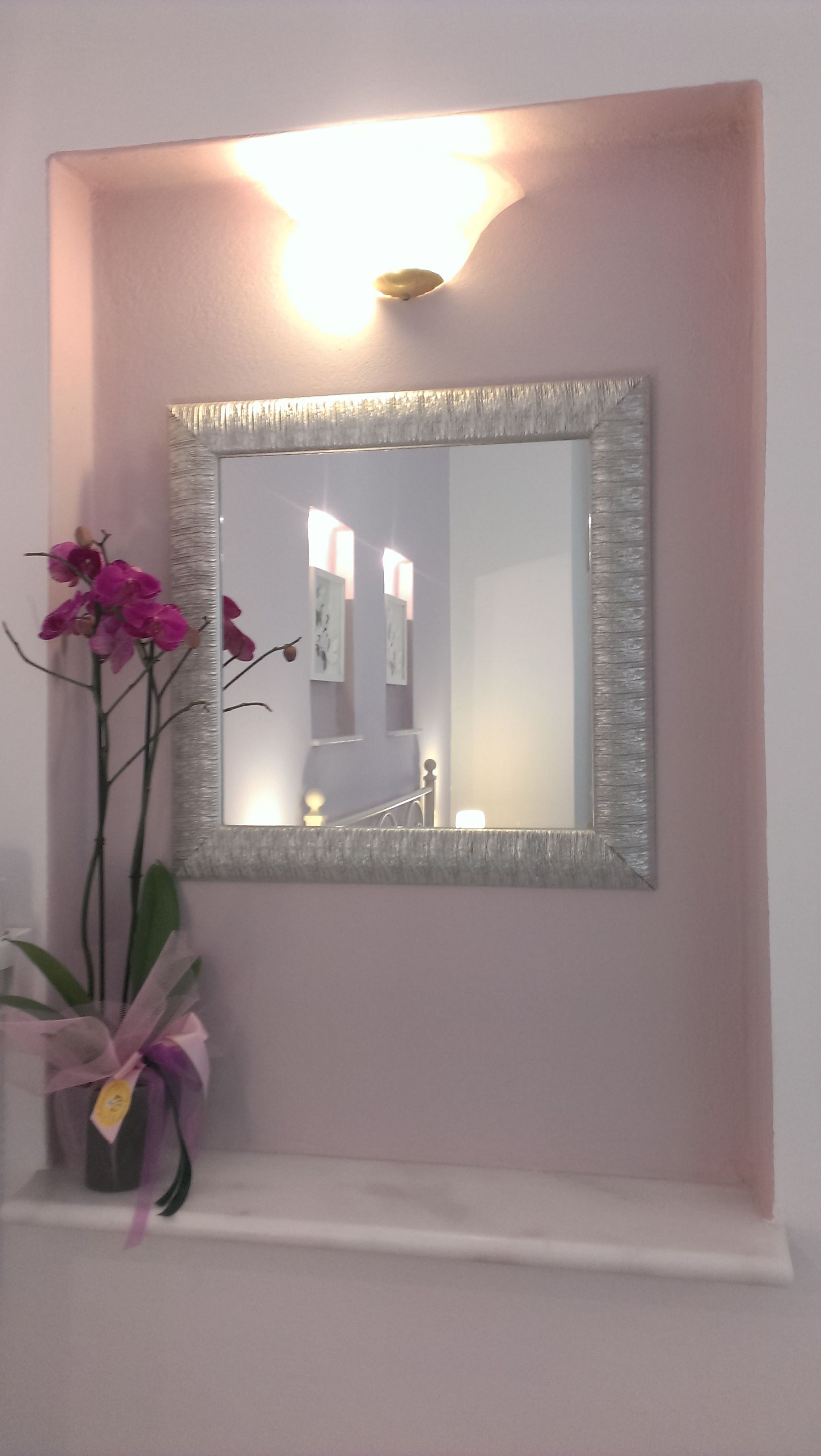 Ein Spiegel mit strukturierter Rahmen, an einer Wand befestigt, der eine Treppe und eine Tür reflektiert.