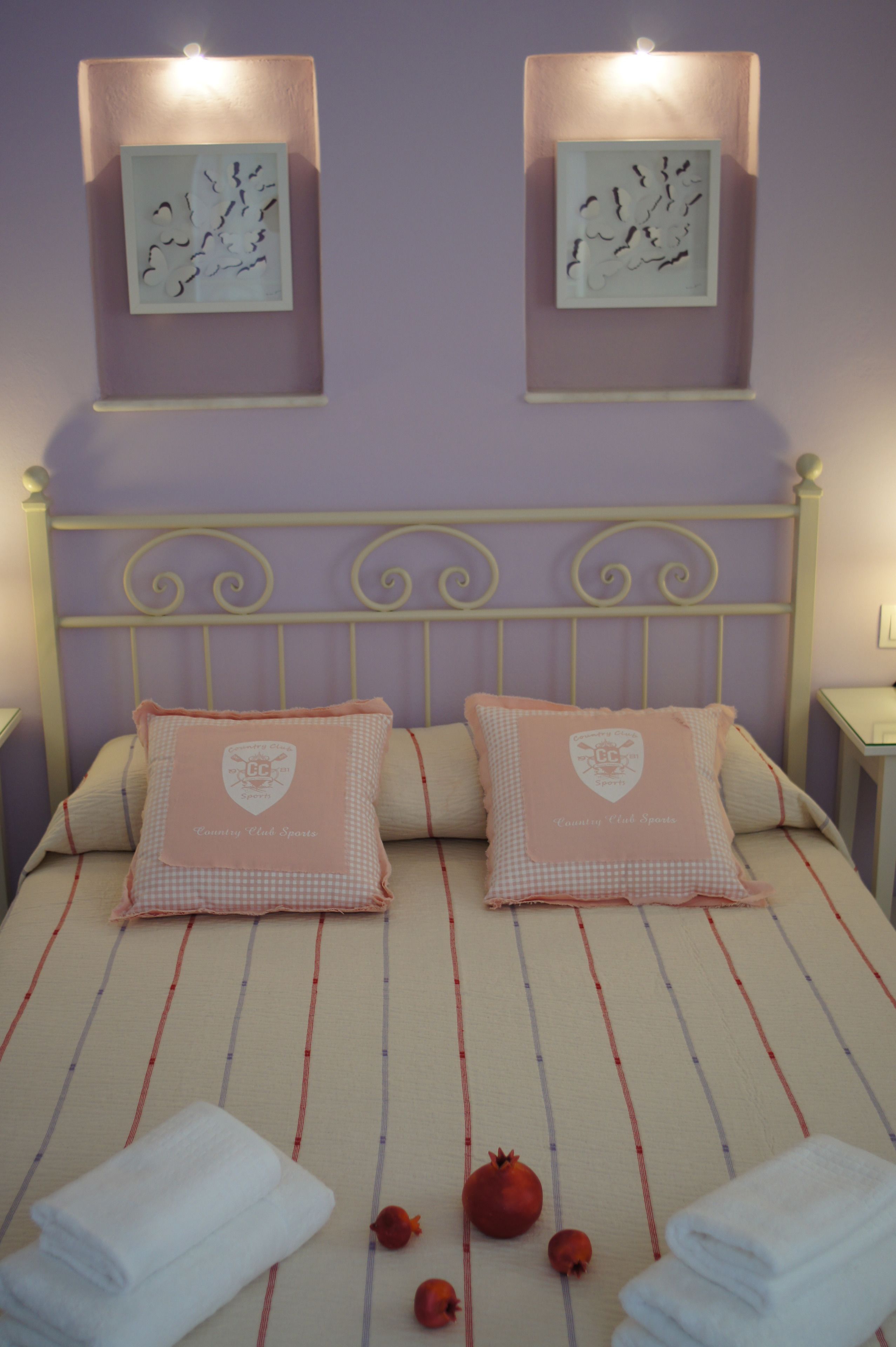 A bedroom with a bed, pillows, a headboard, and two framed pictures on the wall.