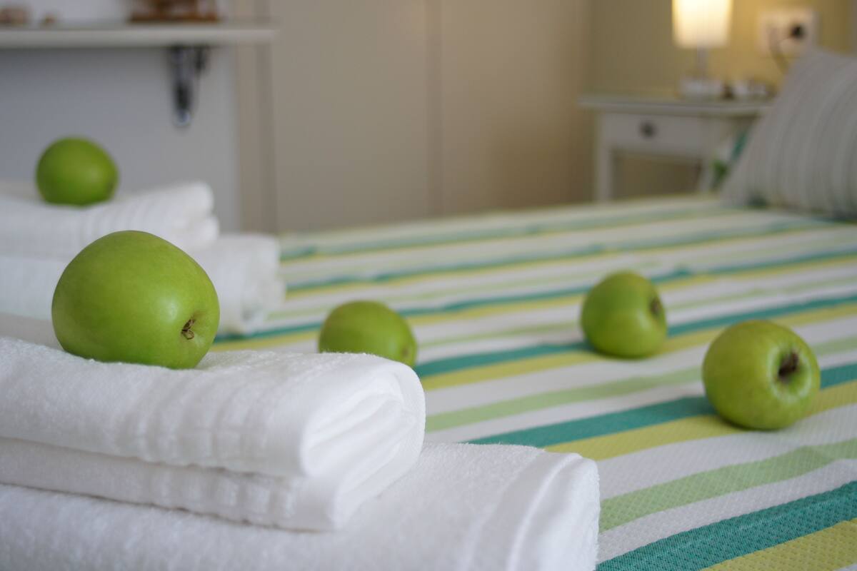 A bed with green apples and white towels.