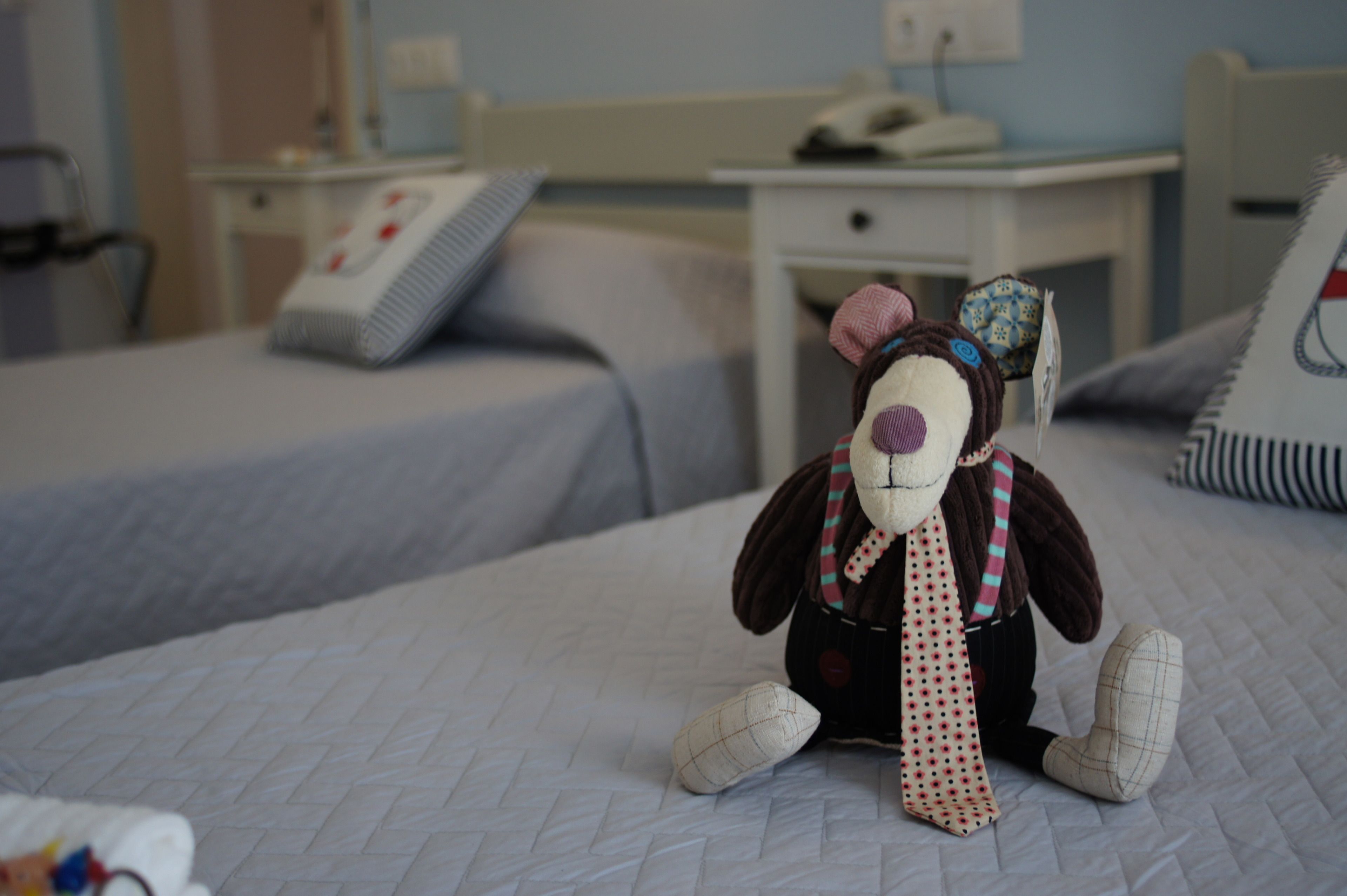 A hotel room with a bed, a bedside table, and a lamp.