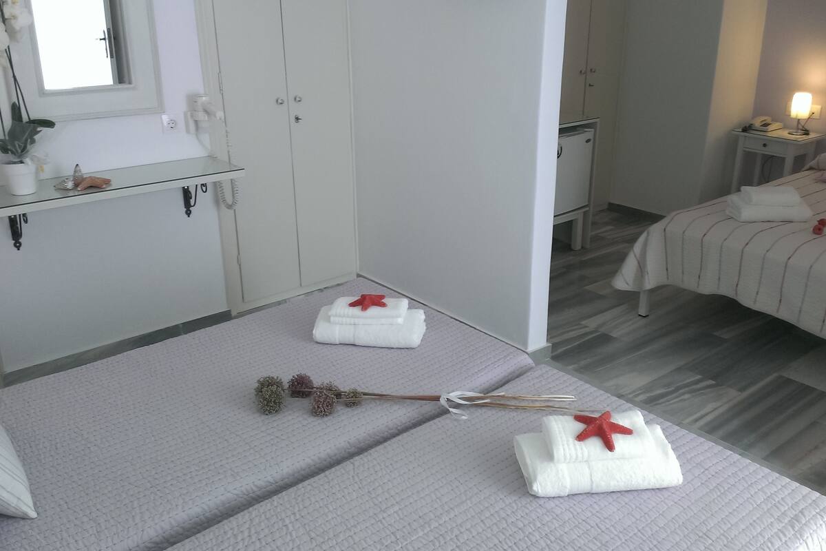 A hotel room with a bed, a small table with a lamp, a wardrobe, and a window with a view.