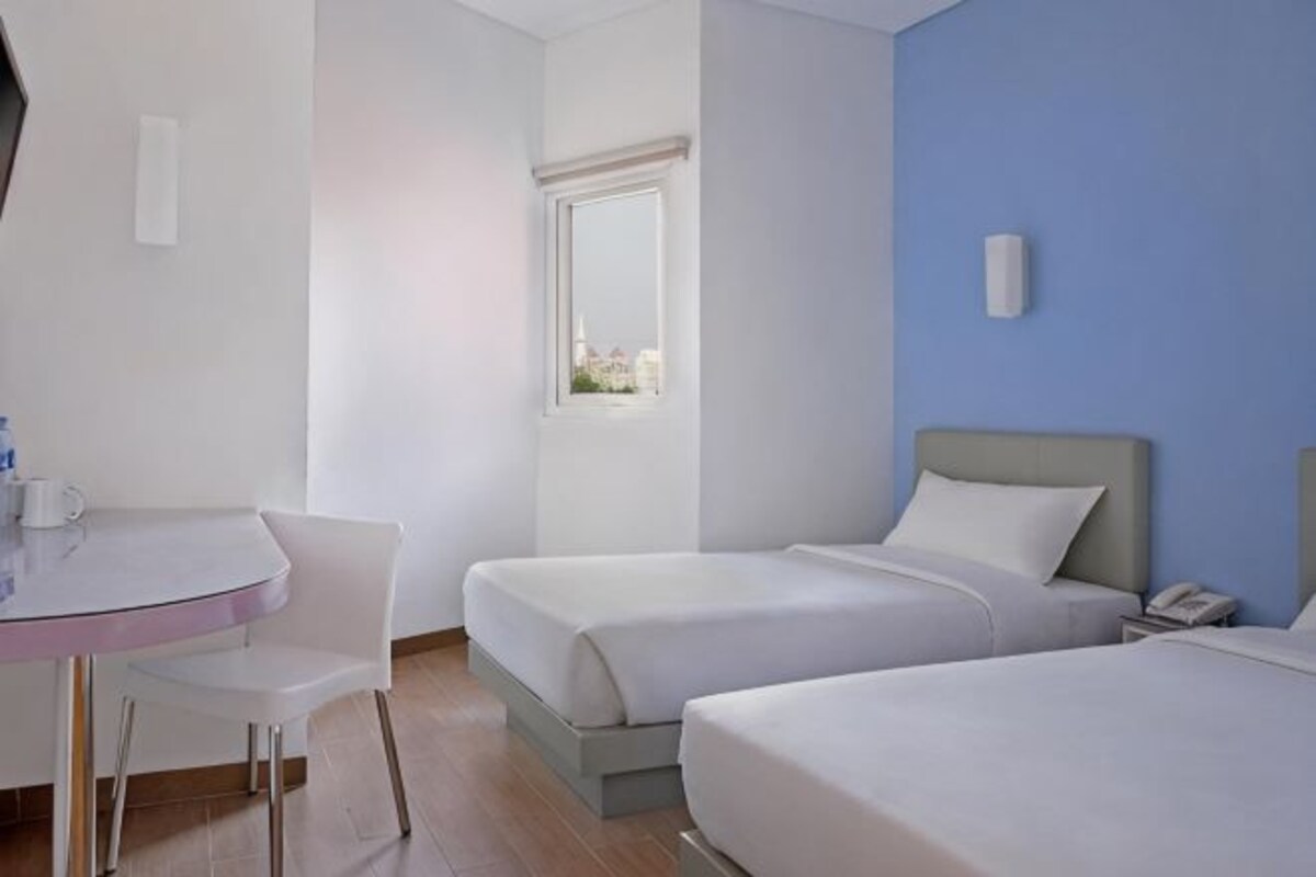 A hotel room with two beds, a desk, and a chair.