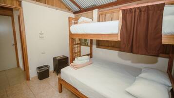 Habitación con literas, techo de madera, un cubo de basura y una puerta.