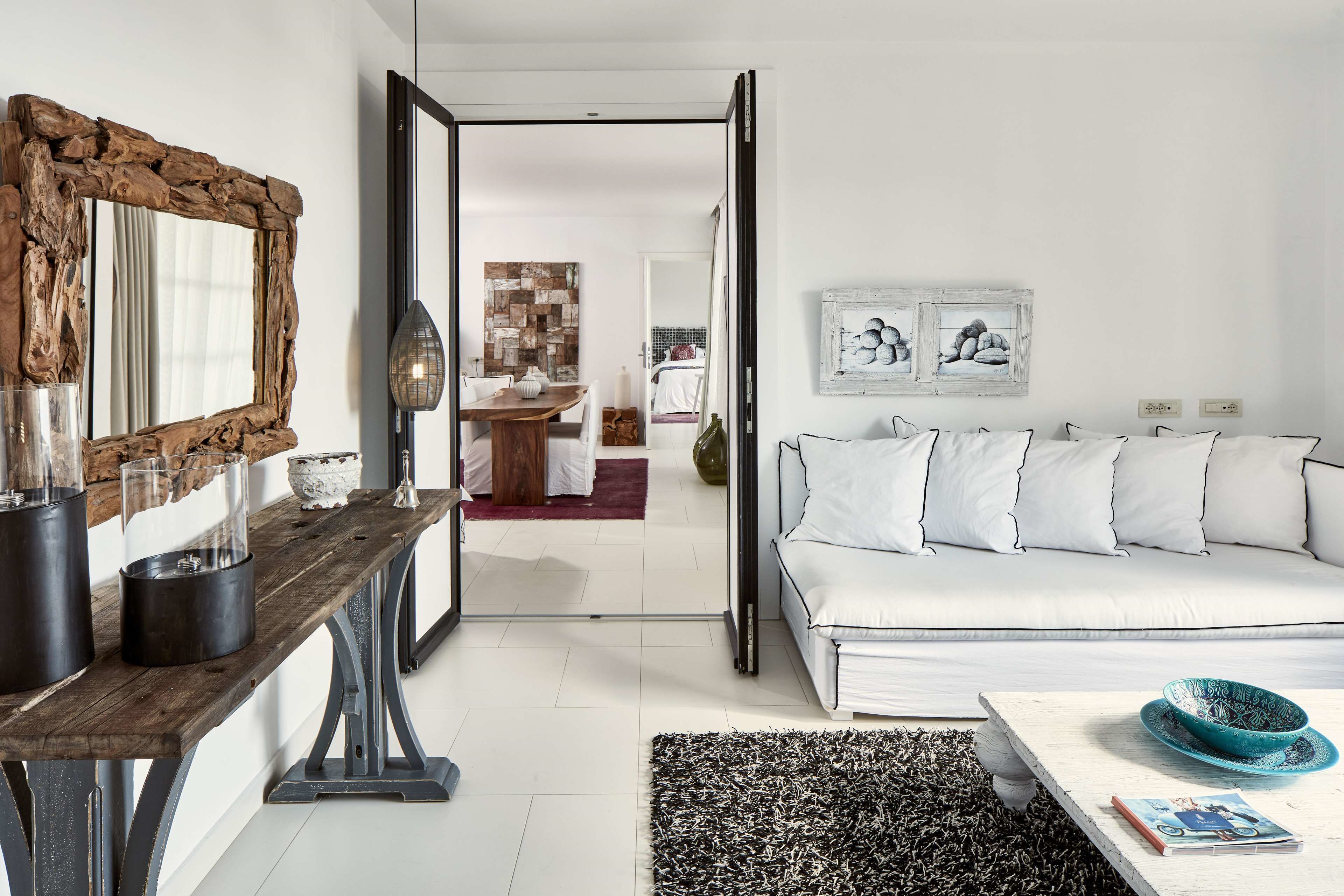 A modern living room with a wooden coffee table, white sofa, and a large mirror.