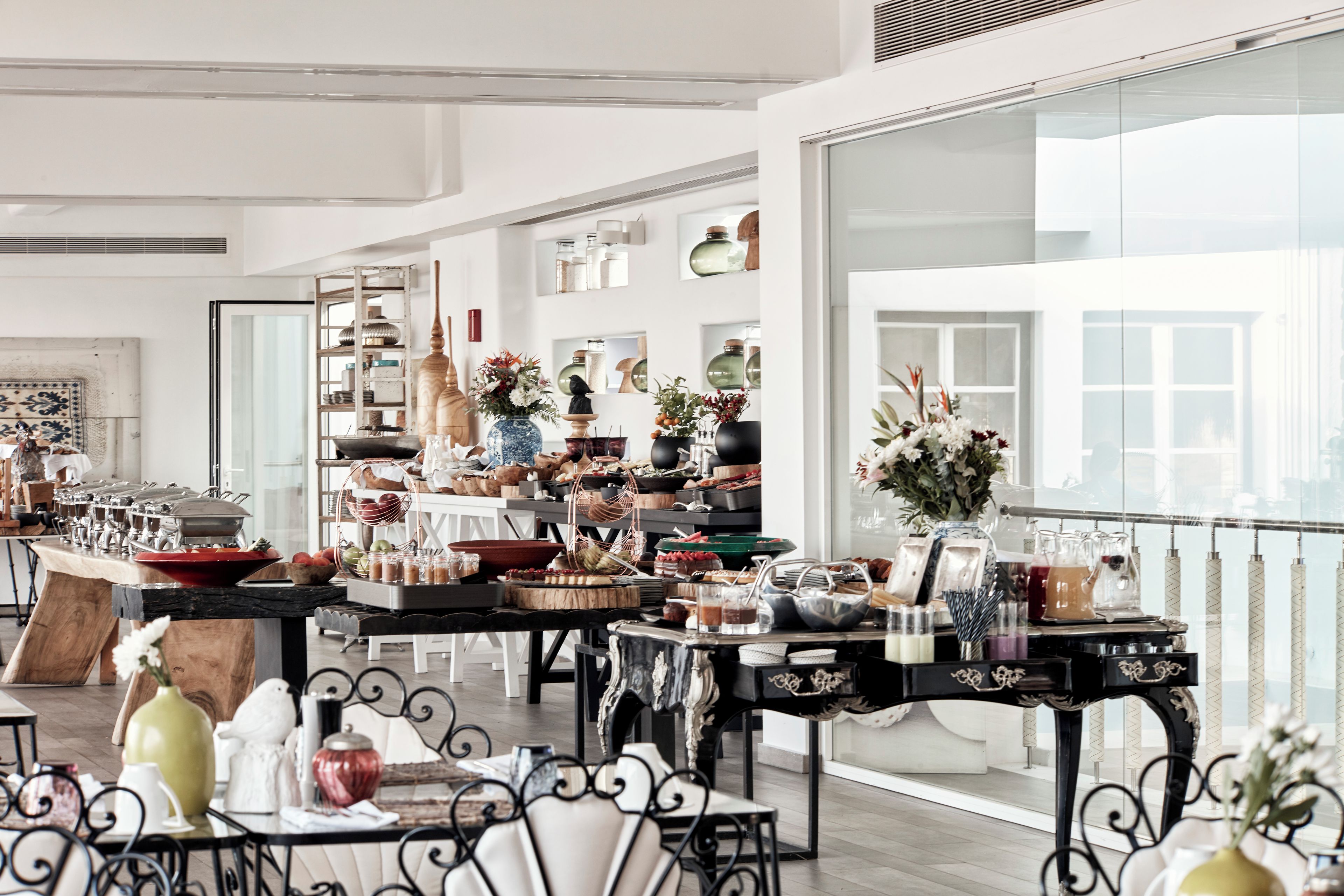 A spacious room with high ceilings and large windows, featuring a variety of tables and chairs arranged for dining or socializing.