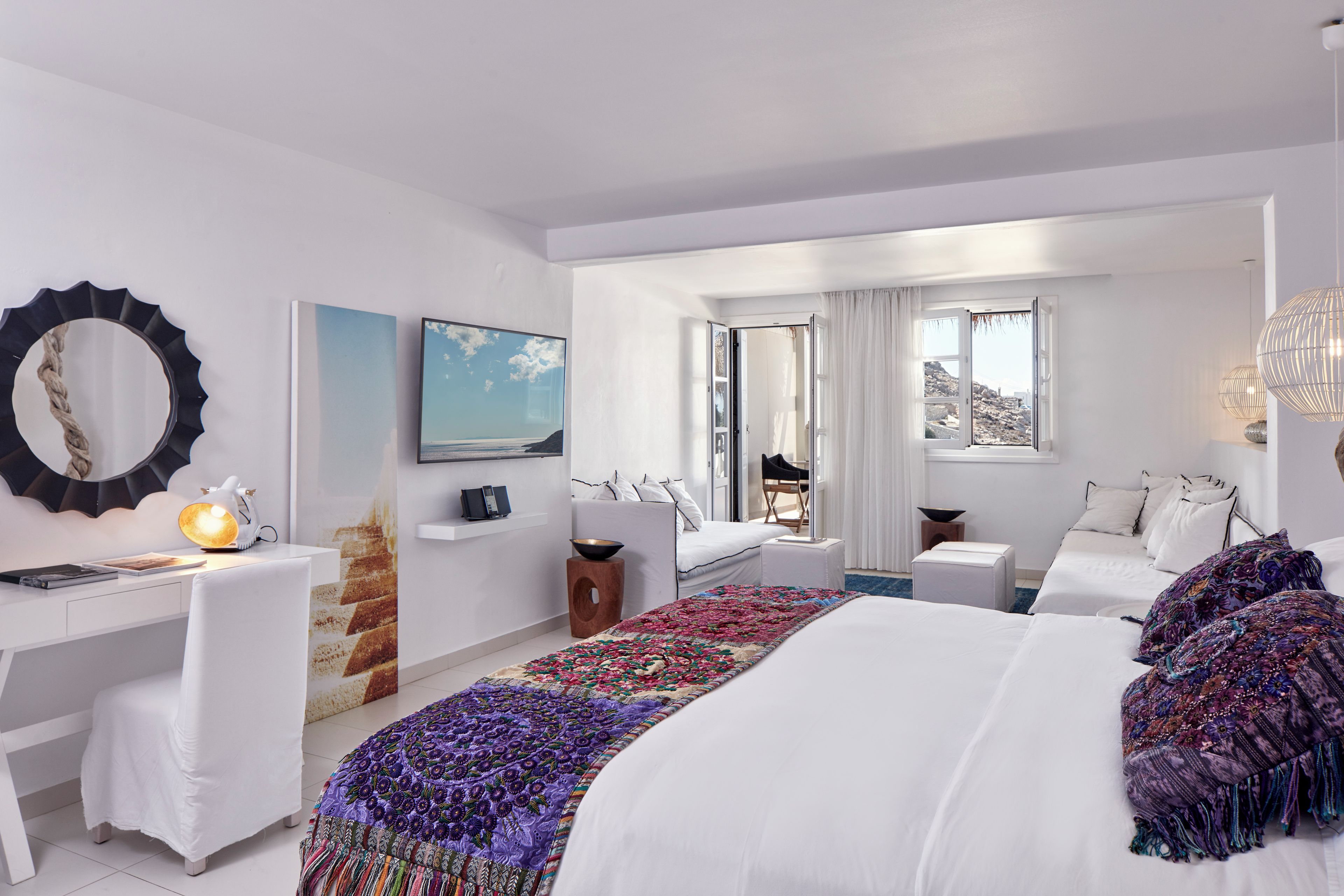 Habitación de hotel moderna con una cama grande, un escritorio, un televisor y vistas al exterior.