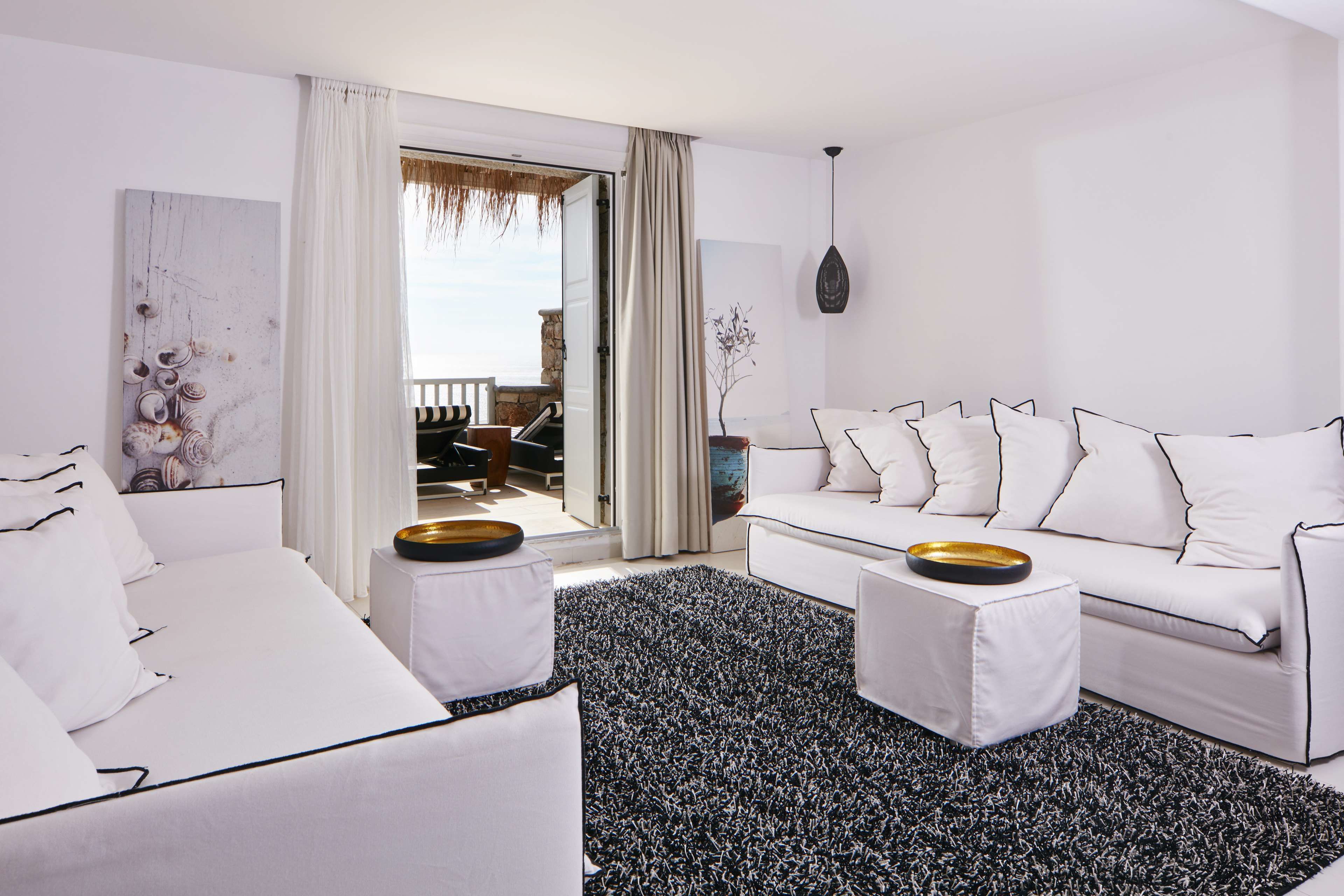 Un salón moderno con un sofá blanco, un tapete blanco y negro y vistas al balcón.