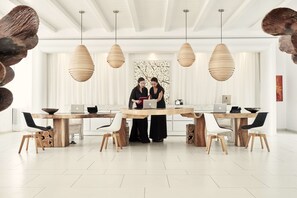 Un comedor moderno con una gran mesa de madera, múltiples sillas y lámparas colgantes.