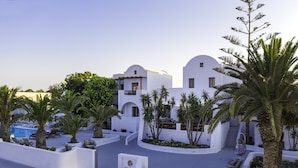 A modern hotel with white architecture, palm trees, and a pool area. - Strogili Hotel - Adults Only (Santorini)