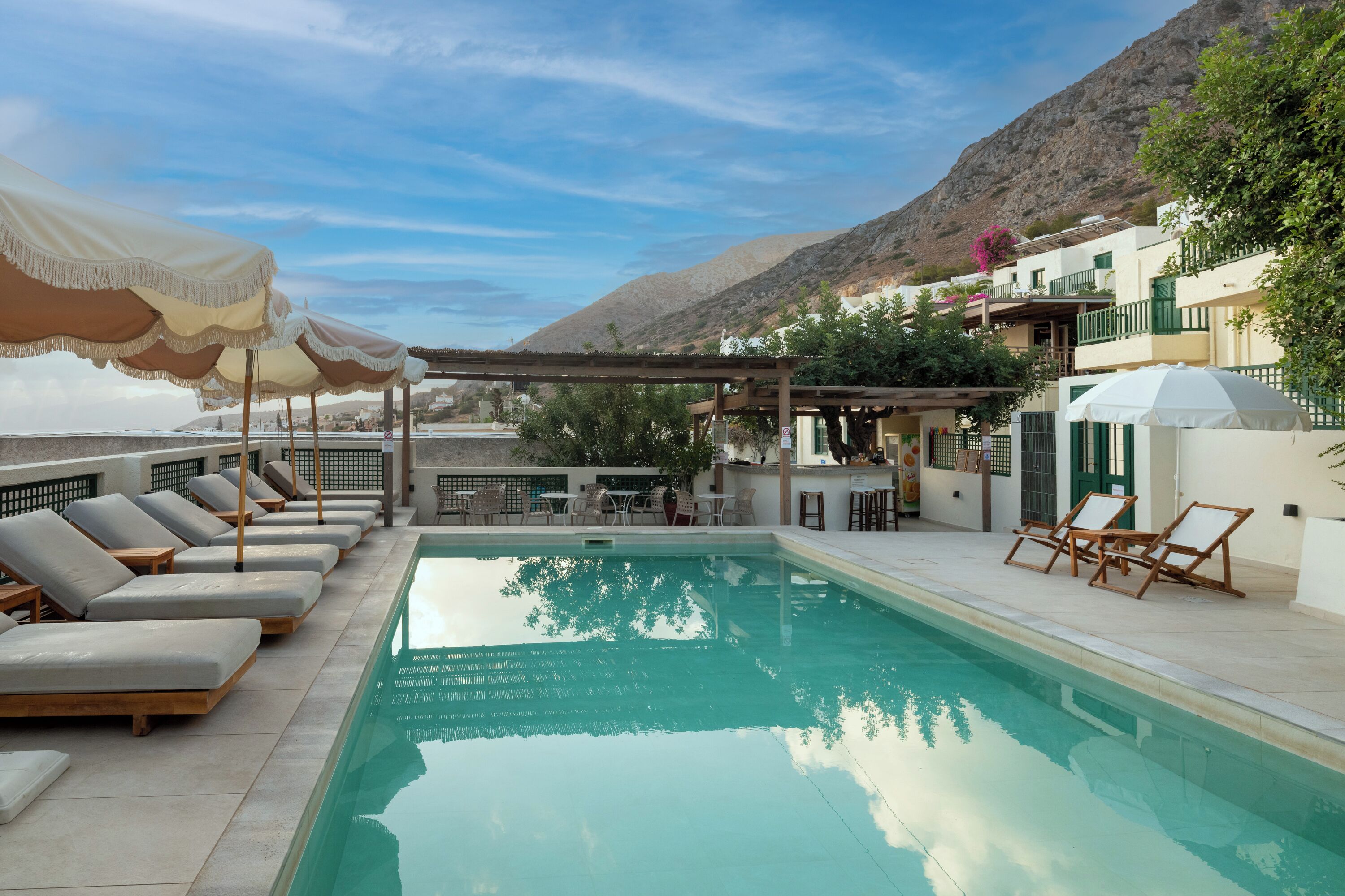 Una piscina al aire libre, sombrillas, sillones reclinables de piscina