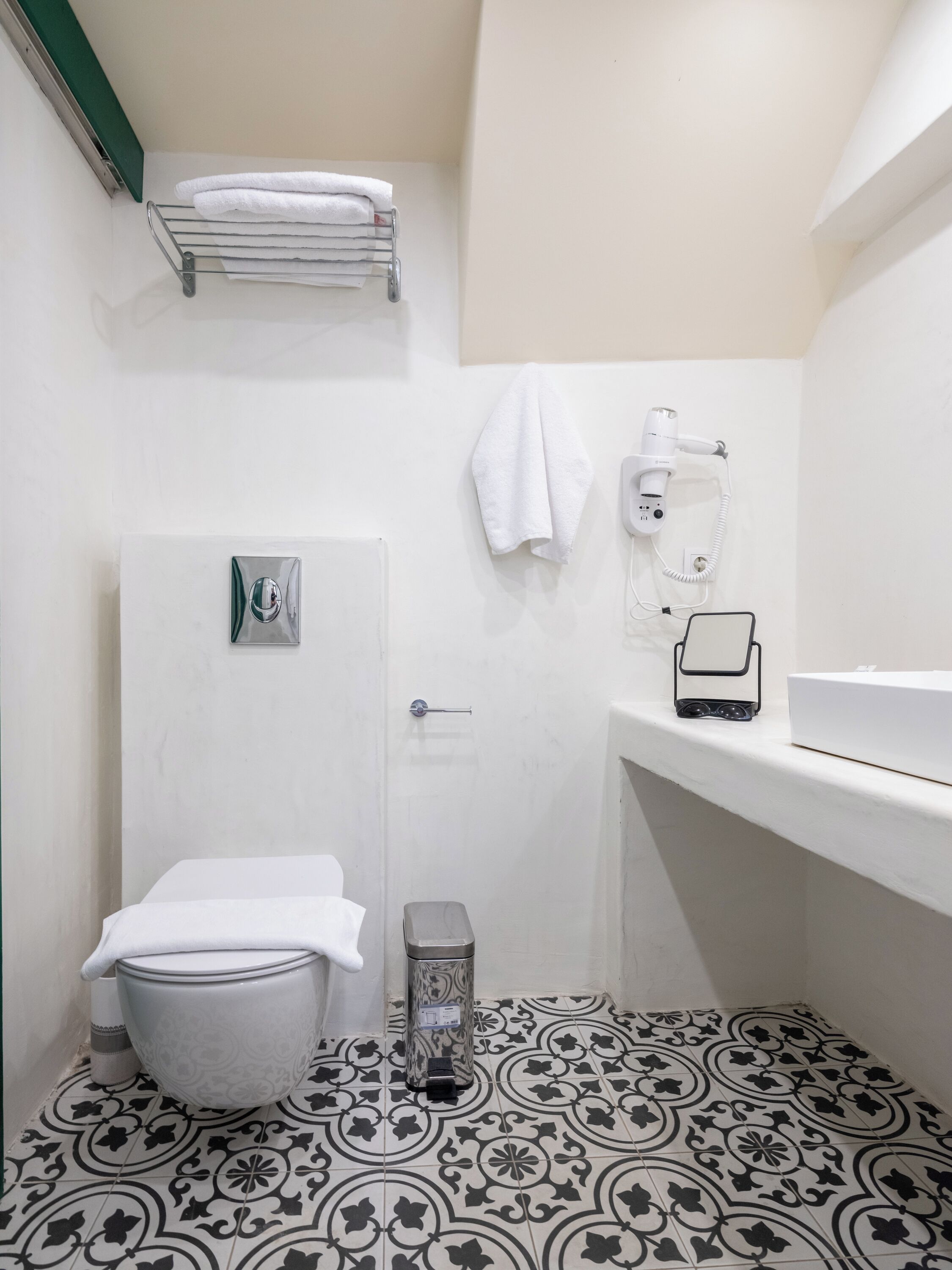 Un bany amb vàter, un lavabo, un assecador i una paperera.